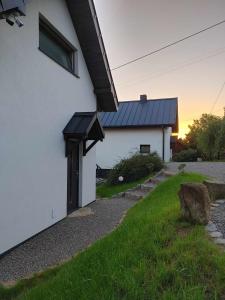 a white house with a black roof and a yard at Domki Na Wiosce 