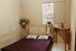 ein Zimmer mit einem Bett und einem Tisch und einem Fenster in der Unterkunft Casa inteira no maior São João do Brasil! in São José de Ribamar