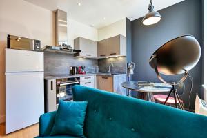a living room with a blue couch and a kitchen at L'urbain in Arras +8 photos