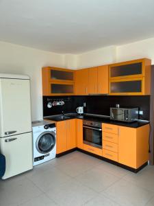 a kitchen with orange cabinets and a white refrigerator at Privat apartament Golf Coast in Kavarna