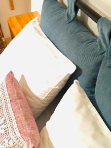 Cama con almohadas blancas y sofá azul en ELÉA Guesthouse himare, en Himare