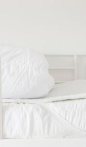 ein Bett mit weißer Bettwäsche und Kissen darauf in der Unterkunft Nordliv Strand in Hasle