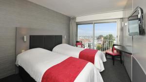 a hotel room with two beds and a balcony at Hôtel Le Nautic in Arcachon