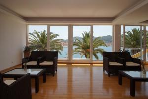 a living room with chairs and tables and a large window at Hotel Posejdon Vela Luka in Vela Luka