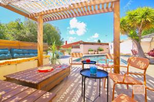 eine Terrasse mit einem Tisch, Stühlen und einem Pool in der Unterkunft Villa Kaz des sables in La Seyne-sur-Mer
