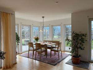 a dining room with a table and chairs and windows at Haus Ammertal in Peißenberg