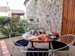 a wooden table with chairs and a table with food on it at Gîte Noisette - Domaine du Pi geonnier de Saint-Vincent in Bourran