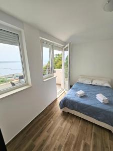 a bedroom with a bed with blue sheets and windows at Apartments Majic Zivogosce in Živogošće