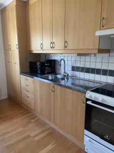 a kitchen with wooden cabinets and a sink at Mysig lägenhet, nära det mesta! in Uddevalla