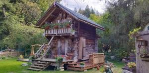 uma pequena cabana de madeira com um alpendre e flores em Amour & Chocolat em Sixt