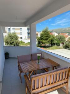 balcón con mesa de madera y 2 bancos en Apartments Paola en Trogir