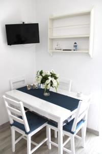 a white dining room table with two chairs and a tv at I Balconcini Sul Porto in Castellammare di Stabia