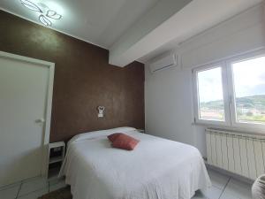 een slaapkamer met een wit bed met een rood kussen erop bij Hotel Ristorante Supersonik in Acri