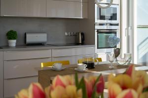 a kitchen with a table with flowers on it at Apartament z tarasem Panorama in Kołobrzeg