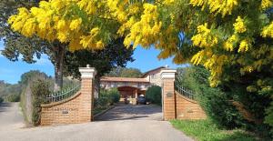 una casa con una valla y un árbol con flores amarillas en Agriturismo Capricorni, en Massa Marittima