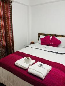 1 dormitorio con 1 cama con almohadas y toallas rojas en ValMas H, en Chachapoyas