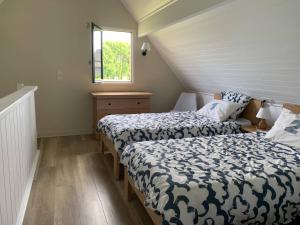 - 2 lits dans une petite chambre avec fenêtre dans l'établissement Cottage YVEL au Pied du lac au Duc, son Golf et sa Base Nautique, à Ploërmel