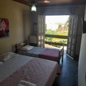 two beds in a room with a view of the ocean at Pousada Miramar in Marataizes