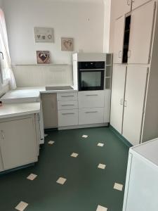 uma cozinha com armários brancos e um piso verde em Appartement AUMALE em Aumale