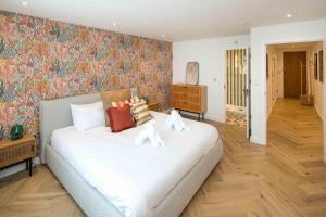 - une chambre avec un grand lit blanc et du papier peint floral dans l'établissement 2Bed 2Bath Stunning Shoreditch Apartment, à Londres