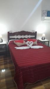 Una cama roja con dos toallas blancas. en Chalés Mimar Lumiar Suítes individuais en Lumiar