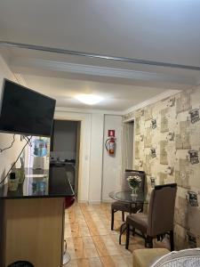 ein Wohnzimmer mit einem Tisch und einem TV. in der Unterkunft Mello's House in Curitiba