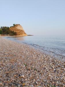 a beach with a rocky shoreline and the ocean at Maison de roche 2 in Nea Kalikratia