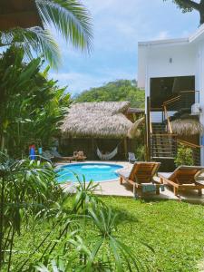 a resort with a swimming pool and chairs and a building at El Chante Surf House in Santa Teresa Beach