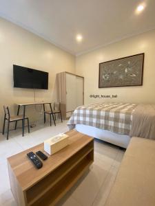Schlafzimmer mit einem Bett und einem Schreibtisch mit einem TV in der Unterkunft Light House Residence Denpasar Bali in Denpasar