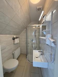 ein Bad mit einem WC, einem Waschbecken und einer Dusche in der Unterkunft Gap Hotel event & more in Langwedel