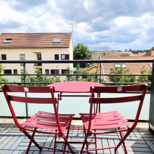 une table rouge et deux chaises assises sur un balcon dans l'établissement Appartement deluxe ac 1 chambre proche Paris Disney 20min rerA ou A4, à Noisy-le-Grand