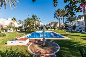 a swimming pool in a yard with palm trees and houses at Mares - Traiña in Caleta De Velez