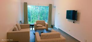 a living room with a couch and chairs and a tv at Kolaahalam Mainland Resorts & Spa in Yercaud