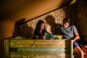 a man and a woman sitting on a bunk bed at Luxury Safari Tent with Hot Tub in Ancient Woodland in Acton Scott