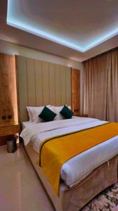 1 dormitorio con 1 cama grande con manta amarilla en رواق الضيافة للشقق المخدومة RWAQ Hotel en Jazán