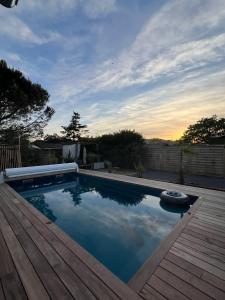 a swimming pool with a wooden deck and the sky at La cabane de Carol au coeur du bassin d'Arcachon in Le Teich