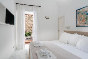 Un dormitorio blanco con una cama con toallas. en Villa Mariuccia Capri en Capri