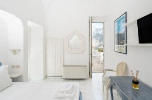 a white living room with a table and a tv at Villa Mariuccia Capri in Capri
