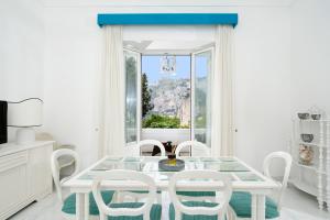 una sala da pranzo bianca con tavolo bianco e sedie bianche di Villa Mariuccia Capri a Capri