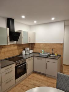 a kitchen with stainless steel appliances and white cabinets at Gästehaus Windrose in Fichtelberg +12 photos