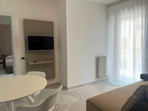 uma sala de estar branca com uma mesa e uma televisão em NUOVO Bilocale Design Piazza Aurora - Adria Holiday Immobiliare Jesolo - Family Apartments em Lido di Jesolo