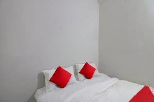 uma cama branca com duas almofadas vermelhas em OYO Flagship Kings Hotel em Nagpur