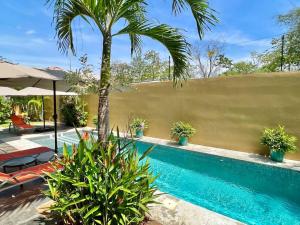 ein Pool mit einer Palme neben einem Zaun in der Unterkunft Villa Gucci Luxury Manuel Antonio w Pool in Manuel Antonio