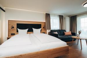 a bedroom with a large white bed and a couch at Hotel Tradizio in Mittelberg