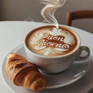 una tazza di caffè e un cornetto su un piatto di Villa Paradiso By Italy a Mostar