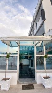 Hotel Biser في باغ: مبنى بأبواب زجاجية ونباتان خزاف