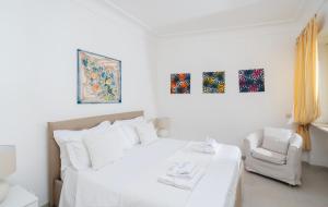 a white bedroom with a bed and a chair at Villa Mariuccia Capri in Capri