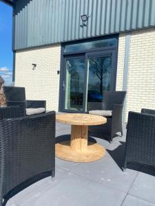 a wooden table in front of a building with chairs at Vakantiehuis Buitengewoon in Beers