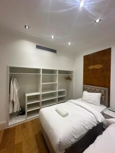 The Chapter Hotels - Mayfair Residences في لندن: غرفة نوم مع سرير أبيض كبير ورفوف