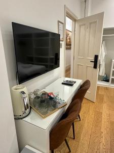 une table blanche avec deux chaises et une télévision à écran plat dans l'établissement The Chapter Hotels - Mayfair Residences, à Londres